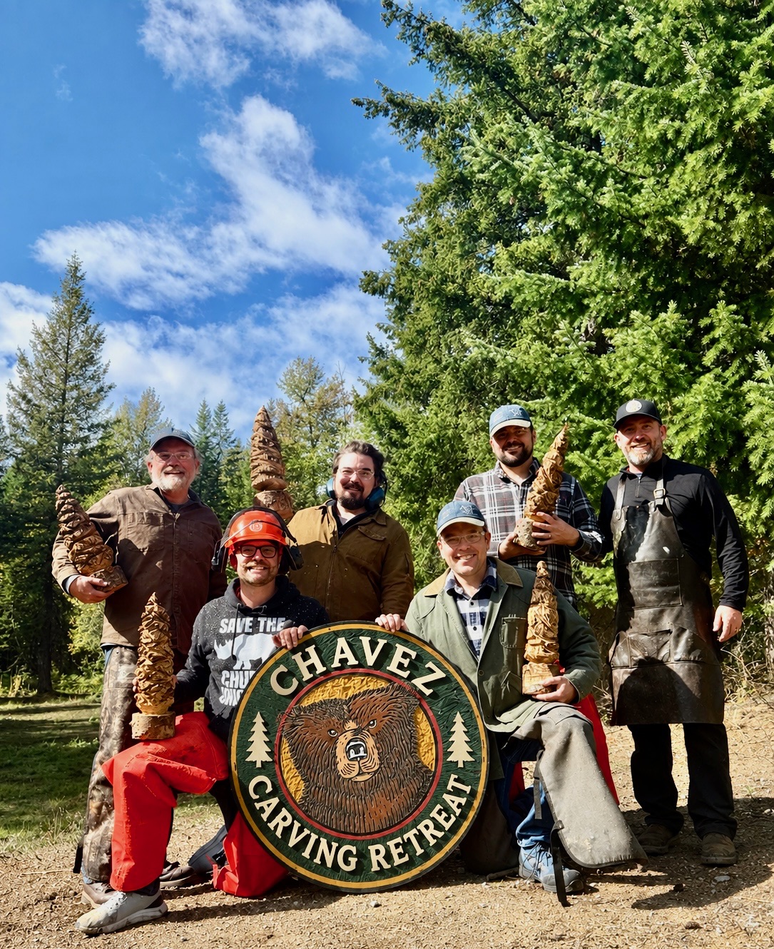 Aaron Chavez and a family group display their finished wood carvings at a bachelor party retreat near Newport, Washington